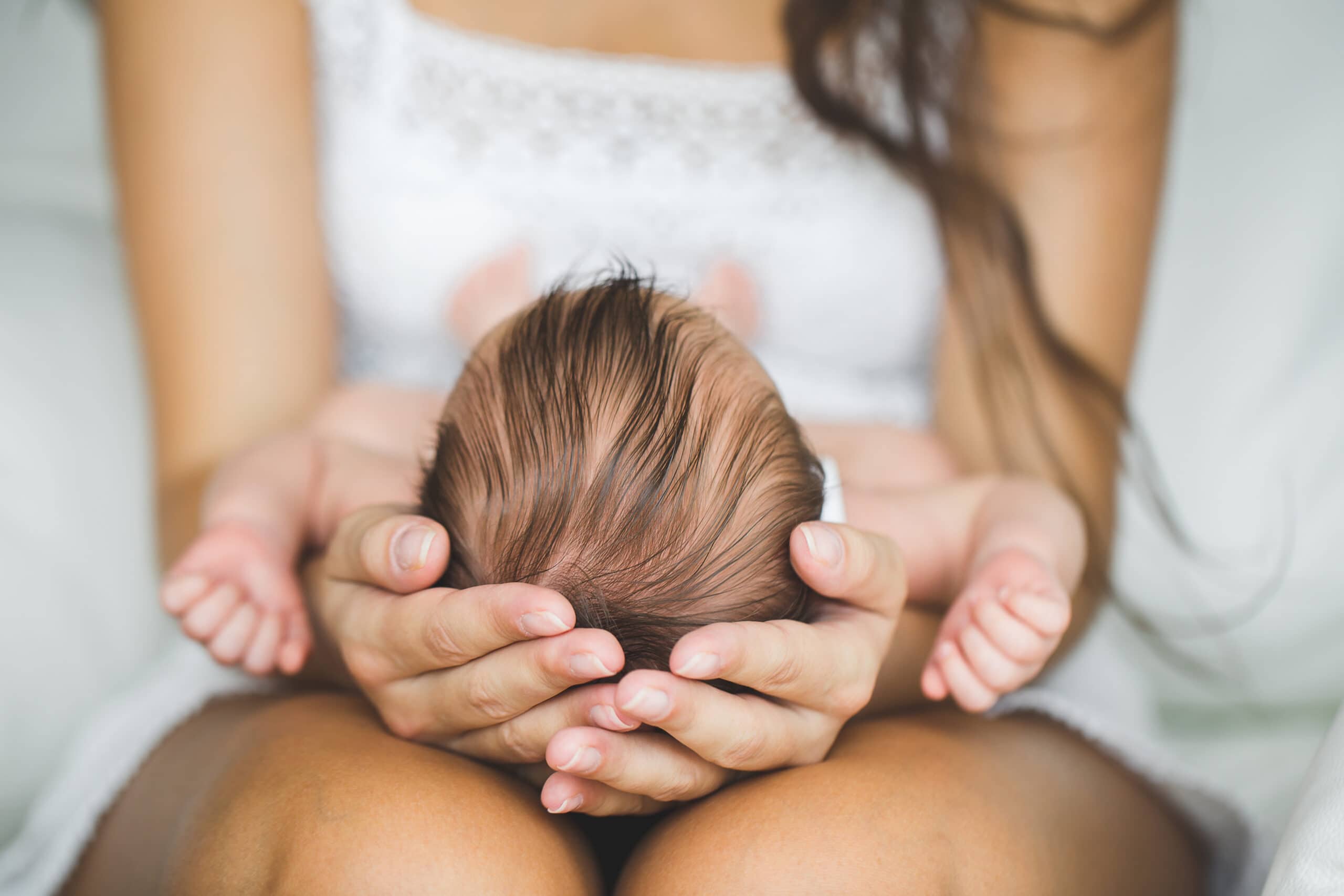 mother holding head of newborn baby